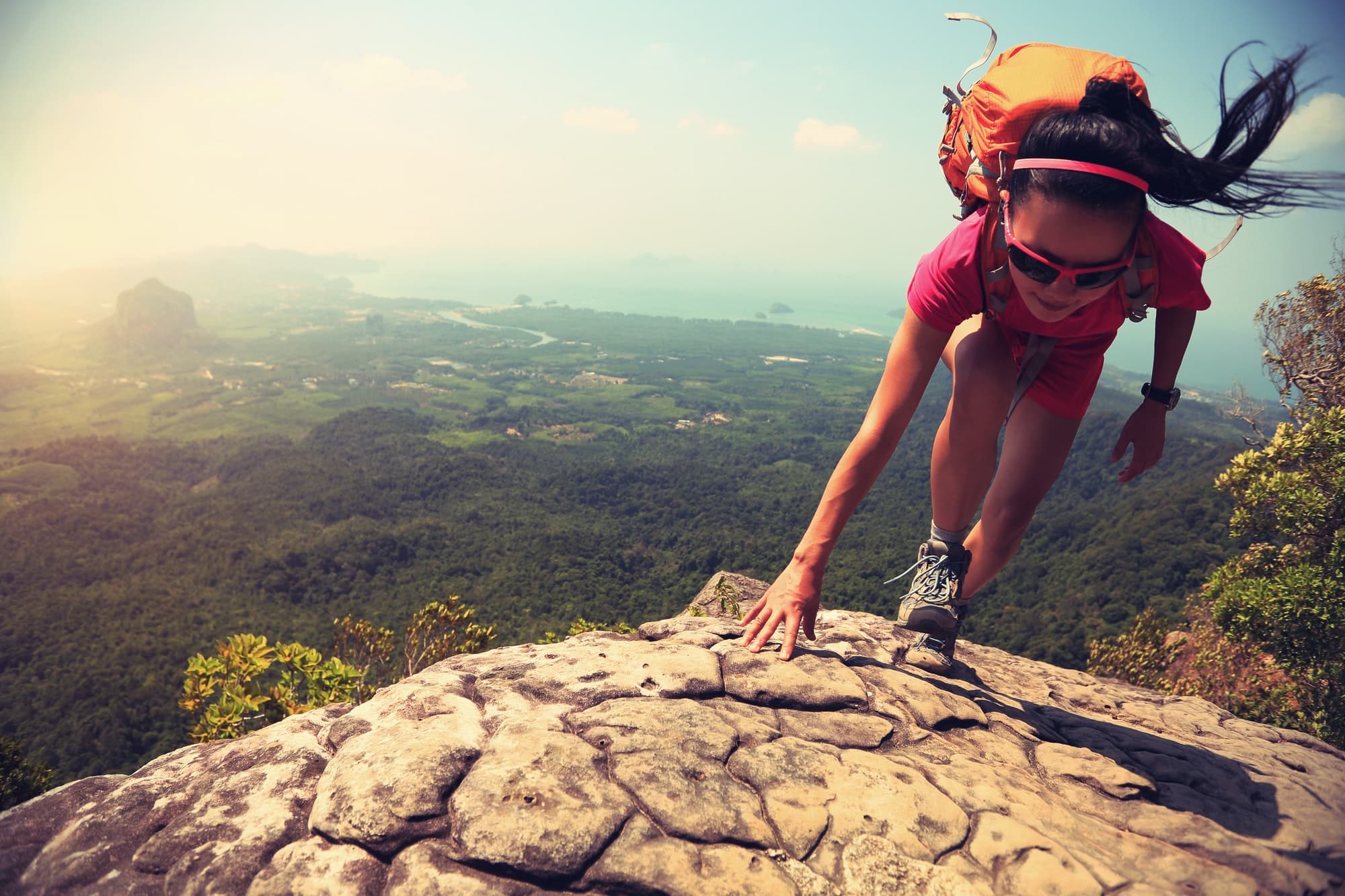 Successful woman climbing up on mountain top cliff edge