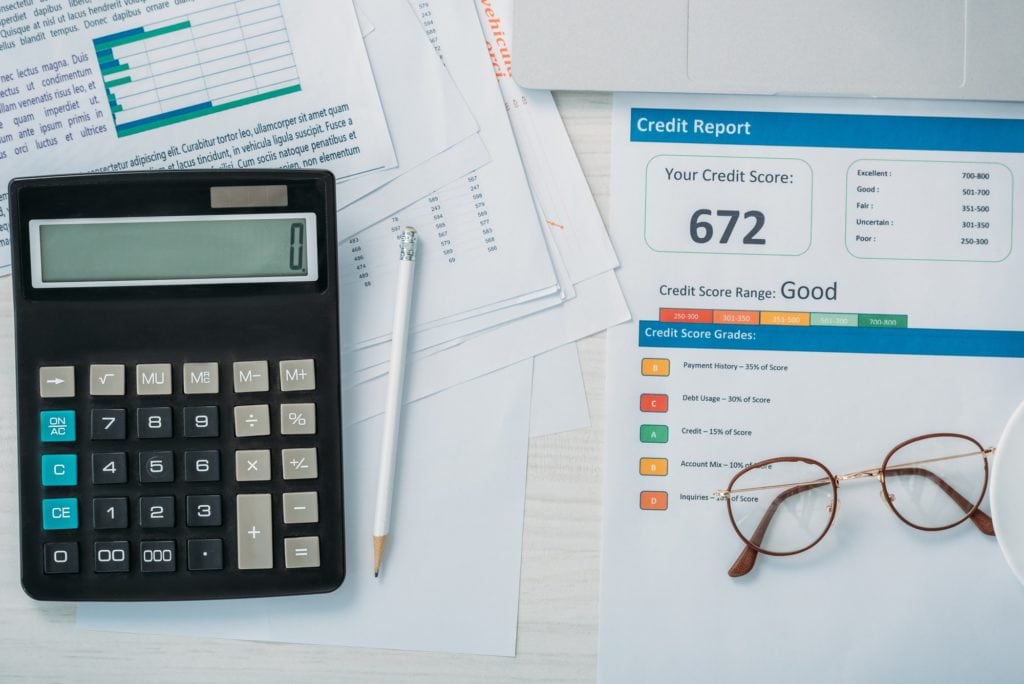 top view of credit report, calculator, glasses and pencil