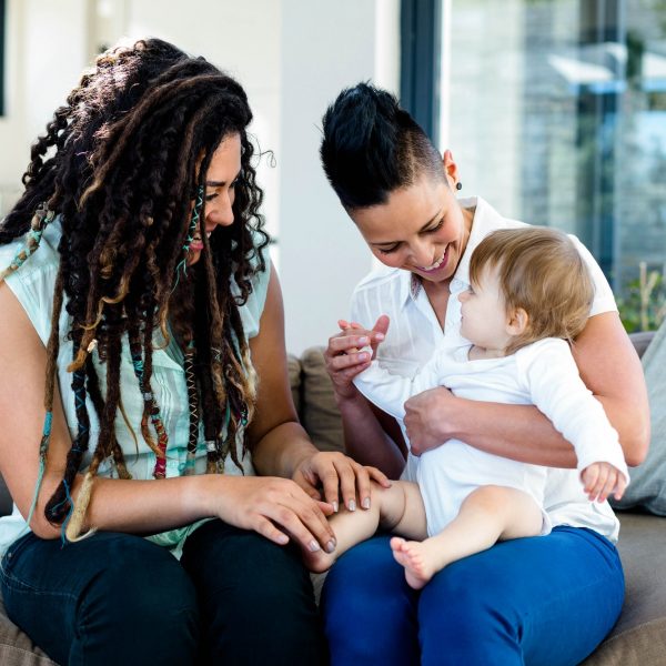 Lesbian couple playing with their baby in living room